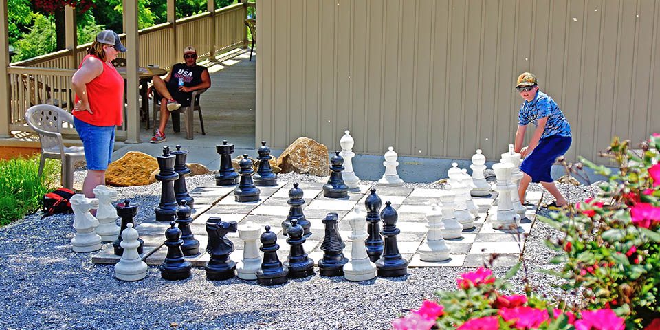 Family playing giant outdoor chess together at Elizabethtown / Hershey KOA Holiday
