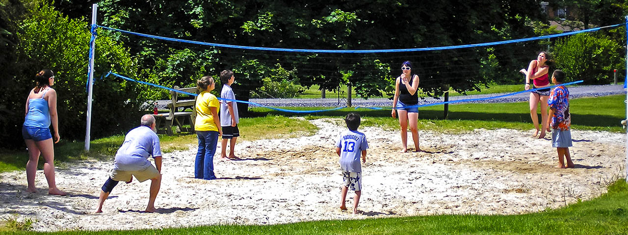 Families enjoying a game of sand volleyball at Elizabethtown / Hershey KOA Holiday during a camping vacation